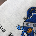 Load image into Gallery viewer, Detailed view of Kappa Kappa Gamma's crest embroidered on a light gray sweatshirt, featuring a blue shield with a golden key and fleur-de-lis, with the sorority name 'Kappa Kappa Gamma' in black lettering beneath.