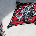 Load image into Gallery viewer, Detailed view of Pi Beta Phi's crest embroidered on a light grey sweatshirt. Featuring an eagle, the seal of Monmouth College, the blazing sun with the latin word lux within, and the Brownlee family crest. Below, the sorority name is embroidered.