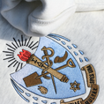 Load image into Gallery viewer, Detailed view of Sigma Delta Tau's crest embroidered on a light grey sweatshirt. Featuring a light blue and gold shield with a red flame and torch, flanked by seven drops to either side and the motto "Patriae Multae spes Una" which translates to "One Hope of Many People" in a ribbon along the bottom. Below the sorority name is embroidered in black.