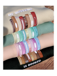 Load image into Gallery viewer, Stack of folded sweatshirts in beige, mint, pink, and dark green, each embroidered with colorful book spines and 'My Weekend is Booked' text.