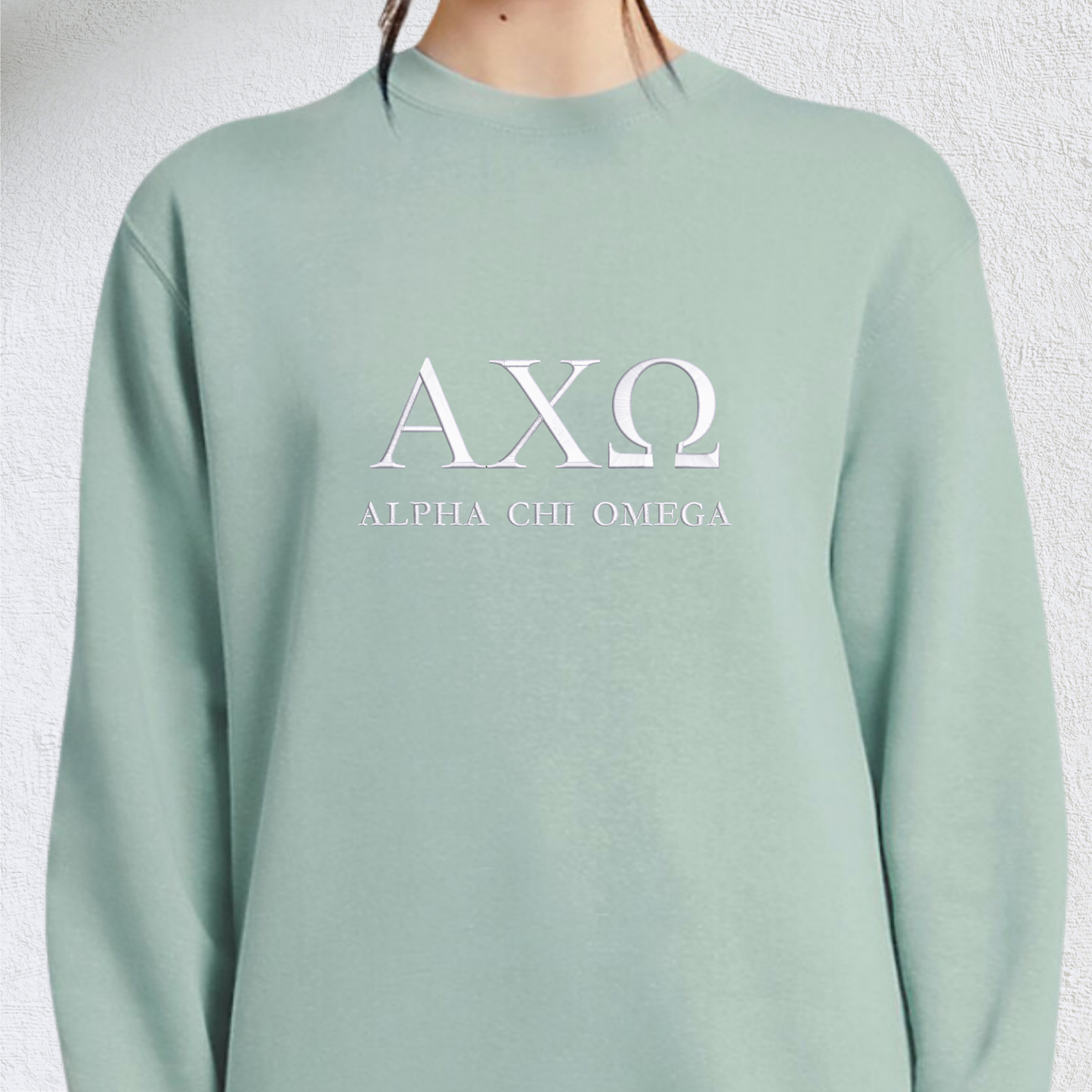 Mint green crewneck sweatshirt featuring the Greek letters 'AXΩ' in large, white serif font at the center, representing the Alpha Chi Omega sorority. Below the letters, 'ALPHA CHI OMEGA' is spelled out in a smaller, matching white serif font.