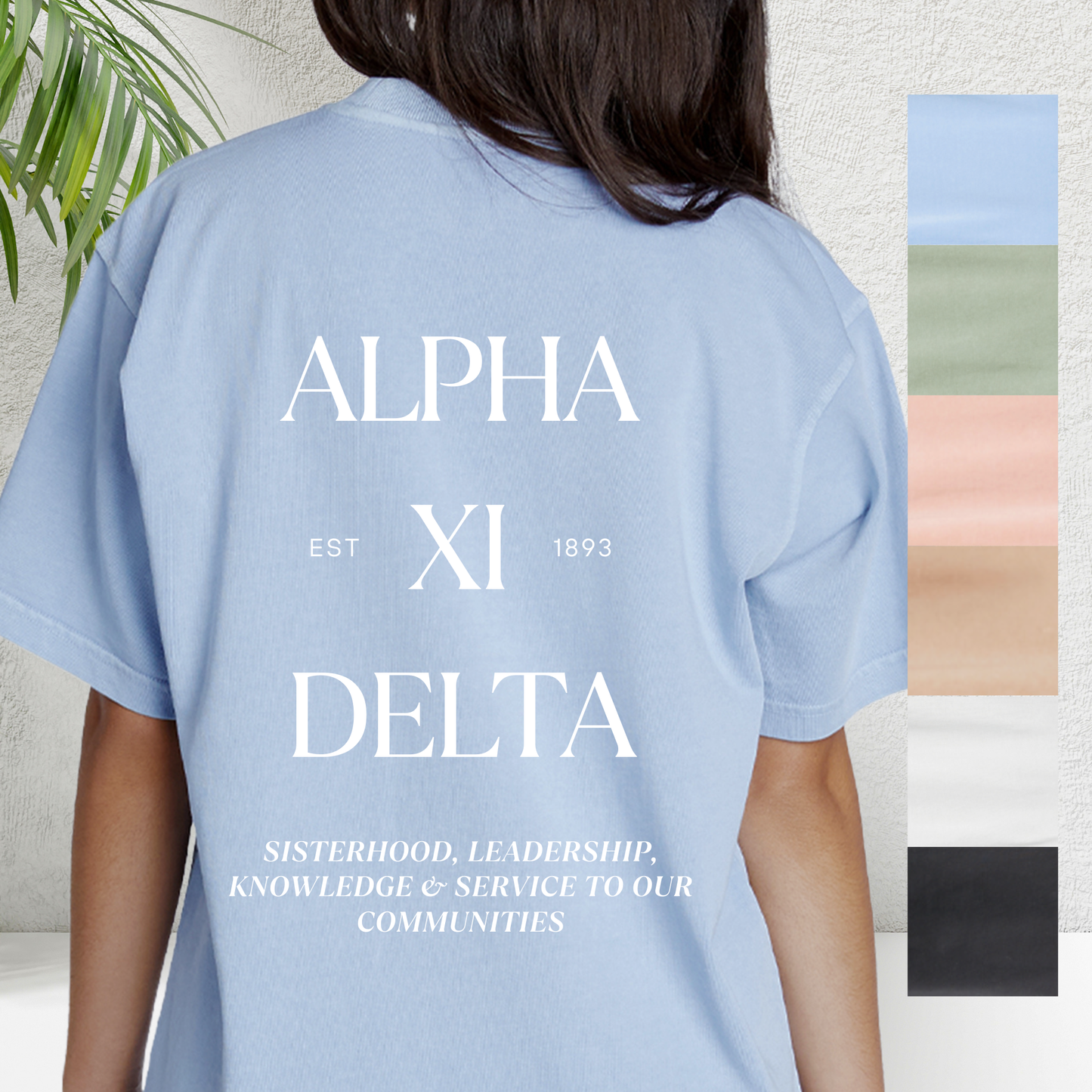 A woman wearing a light blue t-shirt with the Greek letters of her sorority spelled out with the sorority values below in white on the back. The image includes a color swatch below with shades light blue, light green, peach, brown, grey, and black.