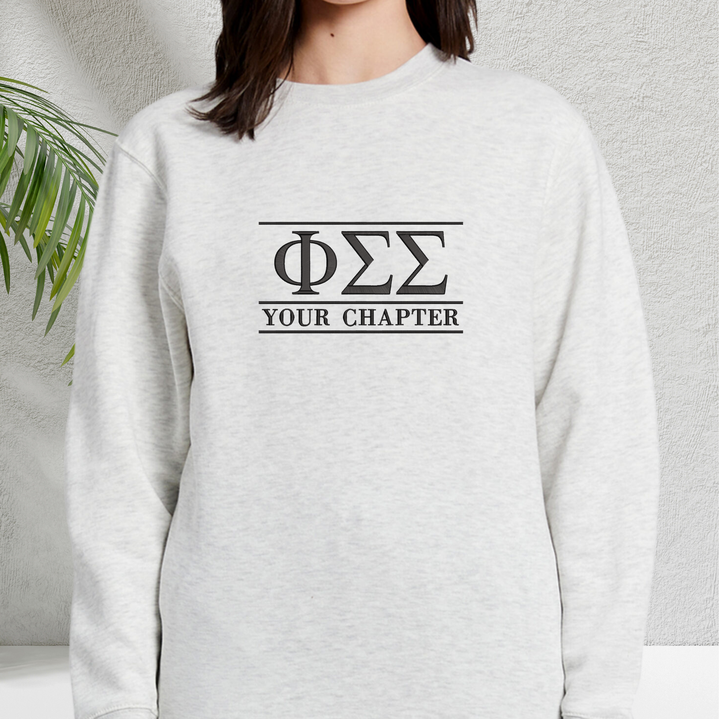 Light grey sweatshirt featuring simple black sorority letters and the sorority chapter on the chest, set against a minimalistic background.