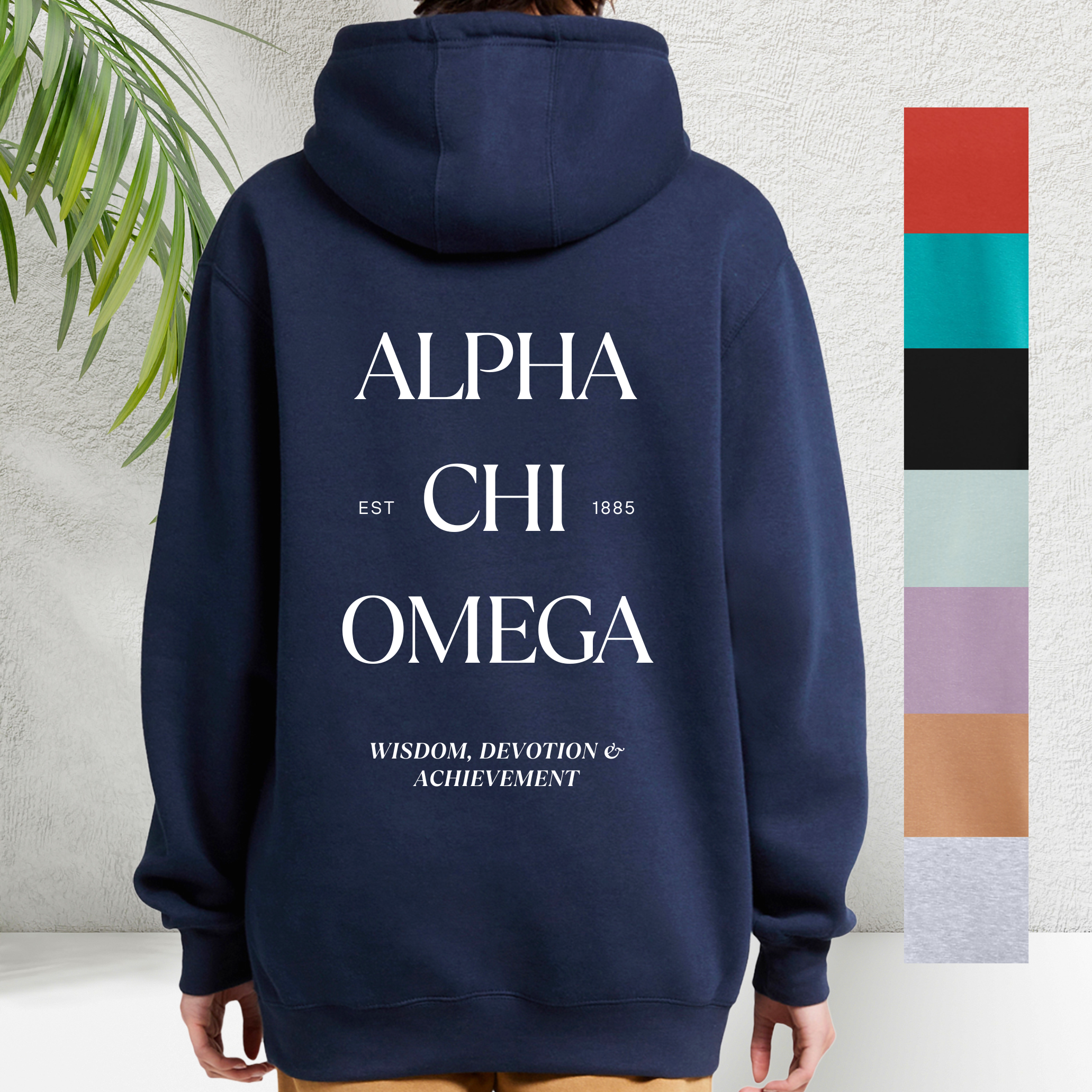 Navy blue hooded sweatshirt viewed from the back with white text across it reading 'ALPHA CHI OMEGA' with 'EST 1885' underneath. Below in smaller text, 'WISDOM, DEVOTION & ACHIEVEMENT' is printed. To the right, a vertical color palette includes six swatches in red, teal, black, light gray, lavender, and beige.